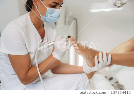Professional care, work in progress. Podiatrist with client in clinic Professional care, work in progress. Podiatrist with client in clinic 137854413