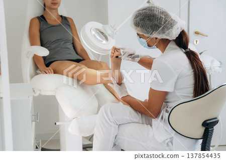 Focused on peeling. Podiatrist with client in clinic Focused on peeling. Podiatrist with client in clinic 137854435