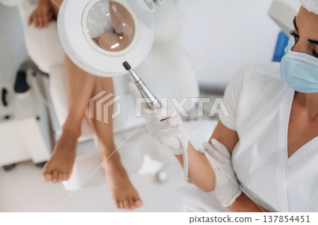 Showing the equipment. Podiatrist with client in clinic 137854451