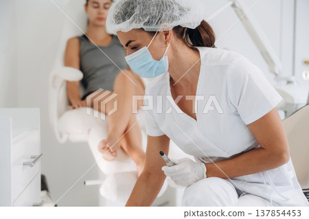 Searching for the right tool. Podiatrist with client in clinic Searching for the right tool. Podiatrist with client in clinic 137854453