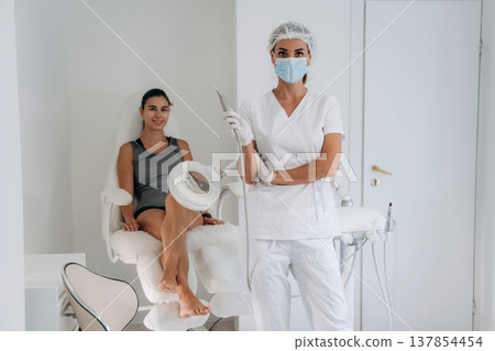 Doctor in mask is standing. Podiatrist with client in clinic 137854454