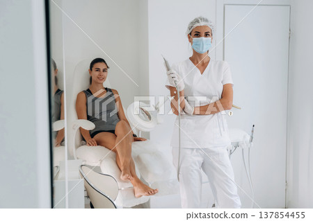 Doctor in mask is standing. Podiatrist with client in clinic 137854455