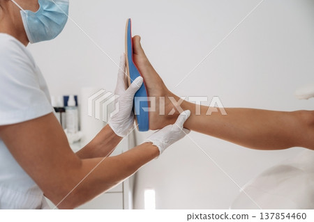 Checks the shape of feet. Podiatrist with client in clinic Checks the shape of feet. Podiatrist with client in clinic 137854460