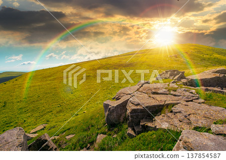 sunset over rocks and rolling hills in mountain landscape in summer. scenery with green grass on alpine meadow under sky with clouds. background for recreation tourism and wanderlust under the rainbow 137854587