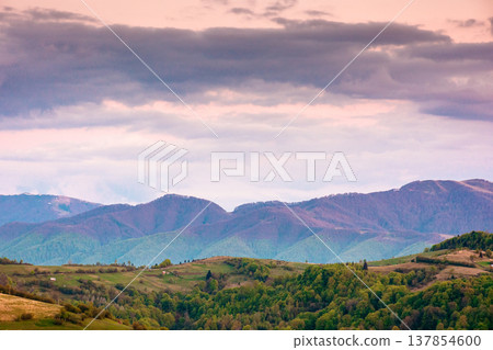 dusk over mountainous countryside scenery. dramatic sky above the distant valley and ridge. remote green meadows and trees on rolling hills. beautiful nature landscape of carpathians during spring 137854600