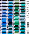 Vertical photo with neat rows of colorful thread spools. Suitable for sewing, textile, tailoring, craft store and haberdashery themes. 137855011
