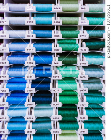 Vertical photo with neat rows of colorful thread spools. Suitable for sewing, textile, tailoring, craft store and haberdashery themes. Vertical photo with neat rows of colorful thread spools. Suitable for sewing, textile, tailoring, craft store and haberdashery themes. 137855011