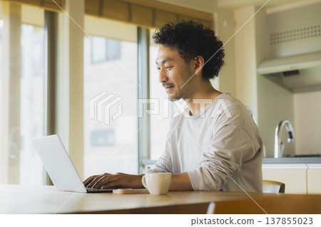 A man working from home in his living room. A man working from home in his living room. 137855023