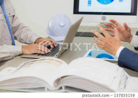Engineers having a meeting while looking at documents at the office Engineers having a meeting while looking at documents at the office 137855159