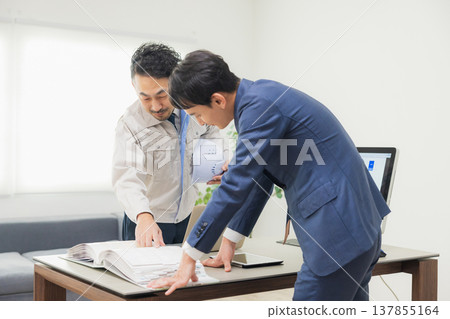 工程師們在辦公室一邊開會一邊查看文件。 工程師們在辦公室一邊開會一邊查看文件。 137855164