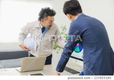 Engineers having a meeting while looking at documents at the office Engineers having a meeting while looking at documents at the office 137855165