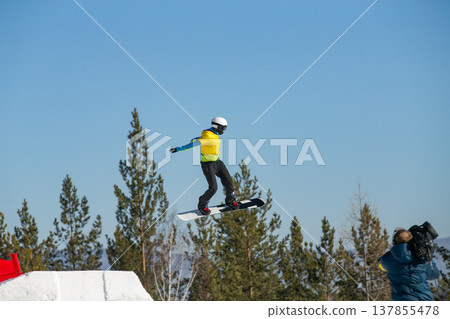 Female snowboarder in yellow vest soaring Female snowboarder in yellow vest soaring 137855478