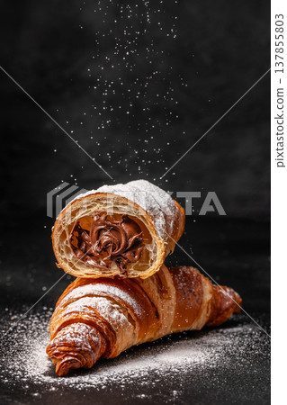 Croissants with Chocolate Filling and Powdered Sugar on Dark Background 137855803
