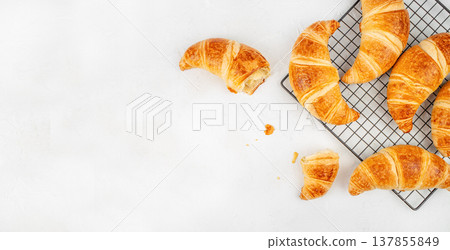 Croissants on Cooling Rack with Bite and Crumbs on White Background Croissants on Cooling Rack with Bite and Crumbs on White Background 137855849