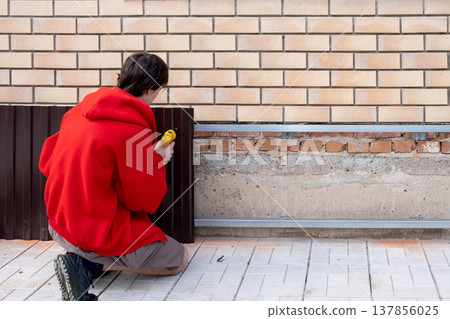 Worker installing house plinth with metal sheets during construction works 137856025