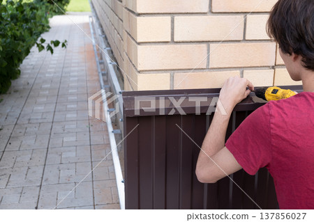 Worker installing house plinth with metal sheets during construction works Worker installing house plinth with metal sheets during construction works 137856027