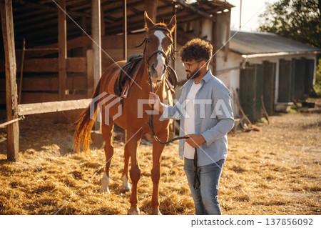 Leading the animal. Guy is with horse on the farm Leading the animal. Guy is with horse on the farm 137856092