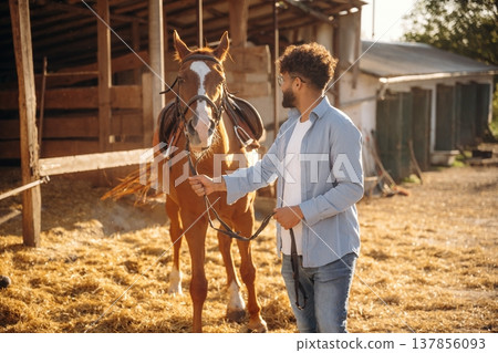 Leading the animal. Guy is with horse on the farm Leading the animal. Guy is with horse on the farm 137856093