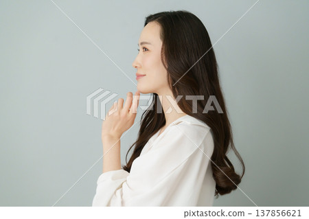 Profile of a young Japanese woman wearing a white shirt against a gray background. Profile of a young Japanese woman wearing a white shirt against a gray background. 137856621