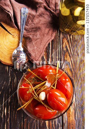 Tasty pickled tomatoes in glass bowl, on wooden table, closeup Tasty pickled tomatoes in glass bowl, on wooden table, closeup 137857450