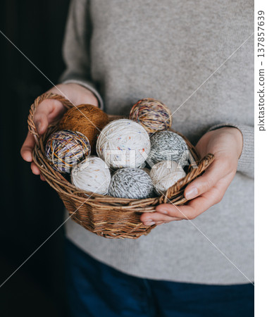 Woman holding a basket with yarn balls for knitting. 137857639
