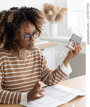 female architect or realtor holds mock up of house in her hands, deals with planning. female architect or realtor holds mock up of house in her hands, deals with planning. 137857759