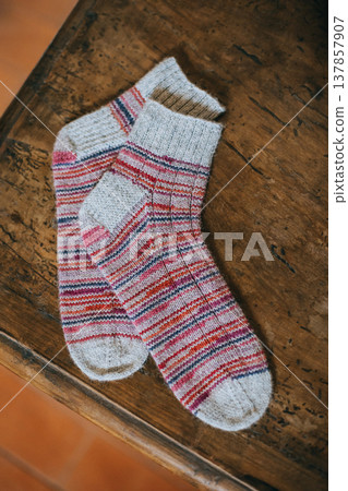 Hand knitted sock with needles on rustic wooden background. Concept for handmade and hygge slow life. Hand knitted sock with needles on rustic wooden background. Concept for handmade and hygge slow life. 137857907