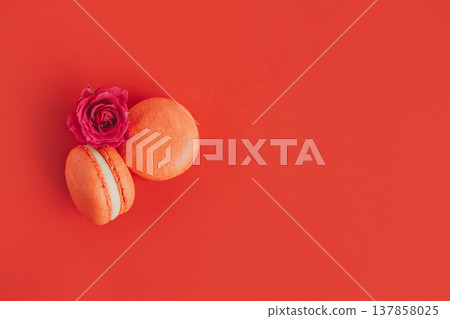 Tasty french macarons with rose flower on a red background. Tasty french macarons with rose flower on a red background. 137858025
