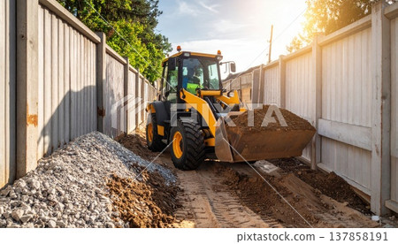 Yellow Construction Vehicle Digging Earth On A Construction Site Near Fence Under Sunny Day 137858191