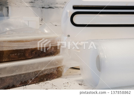 Home vacuum packer for food storage and freezing, canning products. Portions of vacuum-packed raw chicken breast, minced meat and frozen meat broth for cooking and souping. 137858862