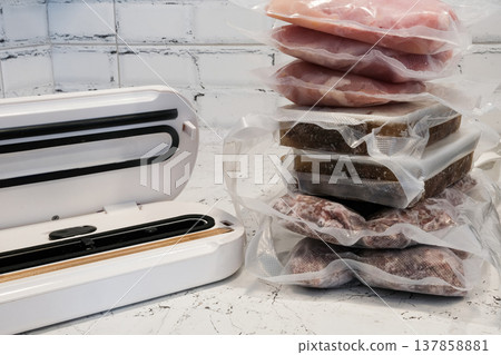 Home vacuum packer for food storage and freezing, canning products. Portions of vacuum-packed raw chicken breast, minced meat and frozen meat broth for cooking and souping. Home vacuum packer for food storage and freezing, canning products. Portions of vacuum-packed raw chicken breast, minced meat and frozen meat broth for cooking and souping. 137858881