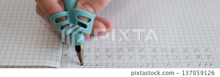 Child practicing handwriting with a special finger grip trainer. Banner. Close-up of kid's hand holding pencil correctly. Development of fine motor skills and calligraphy. Child practicing handwriting with a special finger grip trainer. Banner. Close-up of kid's hand holding pencil correctly. Development of fine motor skills and calligraphy. 137859126