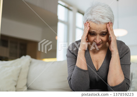 Sad tired ill sick lonely disappointed older senior woman sitting at home alone. Unhappy mature grandmother experiencing grief relative death bad news. Stressed elder lady suffering from loneliness Sad tired ill sick lonely disappointed older senior woman sitting at home alone. Unhappy mature grandmother experiencing grief relative death bad news. Stressed elder lady suffering from loneliness 137859223