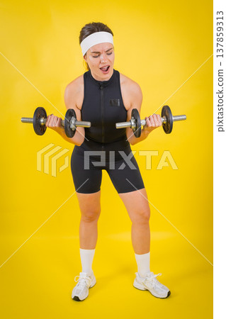 Woman struggling lifting dumbbells during intense fitness workout Woman struggling lifting dumbbells during intense fitness workout 137859313