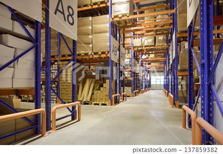 Empty warehouse aisle with labeled shelving and pallets for inventory control Empty warehouse aisle with labeled shelving and pallets for inventory control 137859382