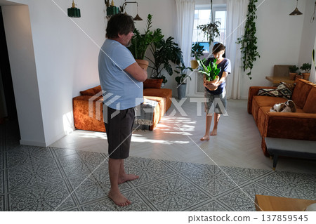 Father and teenage son caring for indoor plants at home, family bonding and sustainable lifestyle Father and teenage son caring for indoor plants at home, family bonding and sustainable lifestyle 137859545