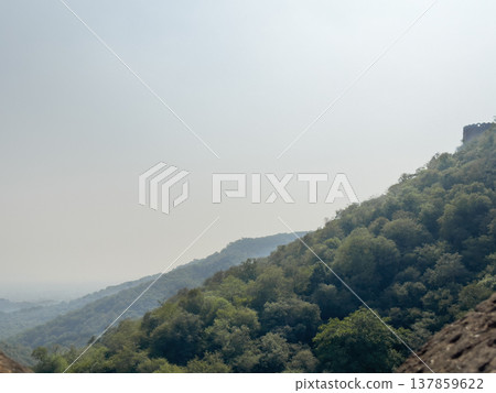 Hazy mountain landscape with layered green hills fading into the distance under a pale sky. Calm 137859622