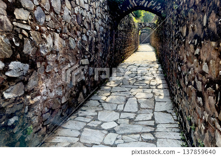 Narrow stone passage with arched openings and rough masonry walls inside a historic fortress. Narrow stone passage with arched openings and rough masonry walls inside a historic fortress. 137859640