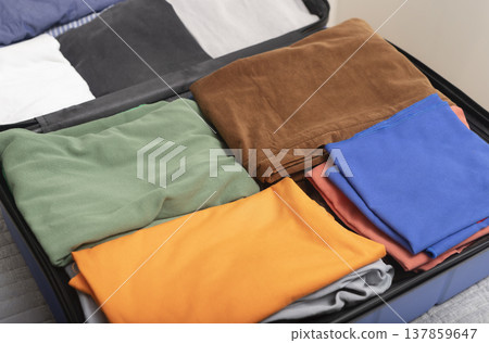 Open suitcase filled with neatly folded colorful clothes arranged in tidy sections. Organized Open suitcase filled with neatly folded colorful clothes arranged in tidy sections. Organized 137859647