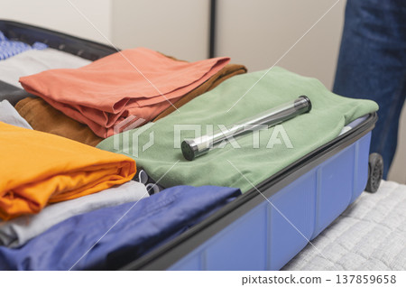 Open suitcase packed with neatly folded clothes and a toothbrush in a protective travel case placed 137859658