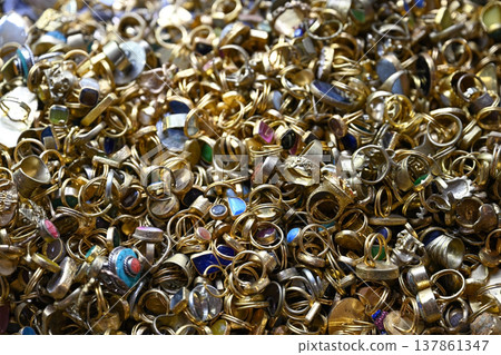 A dense and jumbled heap of gold-toned rings, many set with various colorful gemstones A dense and jumbled heap of gold-toned rings, many set with various colorful gemstones 137861347