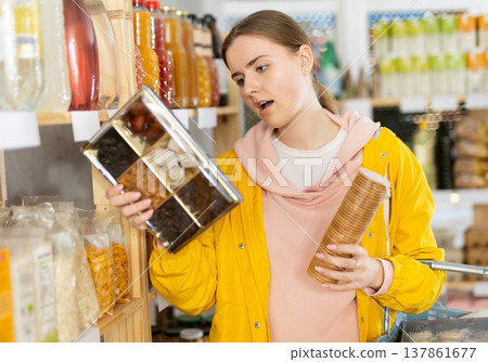 Young woman chooses dried fruits and cookies Young woman chooses dried fruits and cookies 137861677