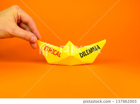 Ethical dilemma words symbol. Concept words Ethical dilemma on beautiful yellow paper boat. Beautiful orange background. Businessman hand. Business and Ethical dilemma words concept. Copy space. 137862003