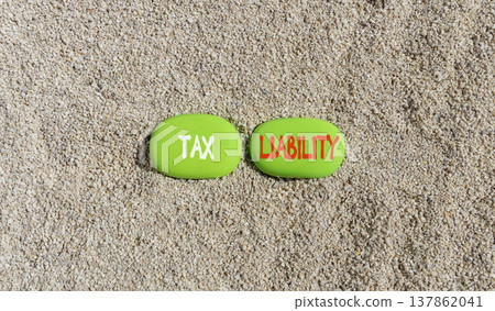 Tax liability words symbol. Concept words Tax liability on beautiful green stones. Beautiful sand background. Business and Tax liability words concept. Copy space. Tax liability words symbol. Concept words Tax liability on beautiful green stones. Beautiful sand background. Business and Tax liability words concept. Copy space. 137862041