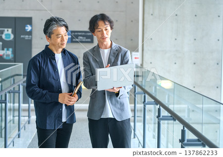 兩位年齡不同的商人正在辦公室開會，各自看著電腦螢幕。 137862233