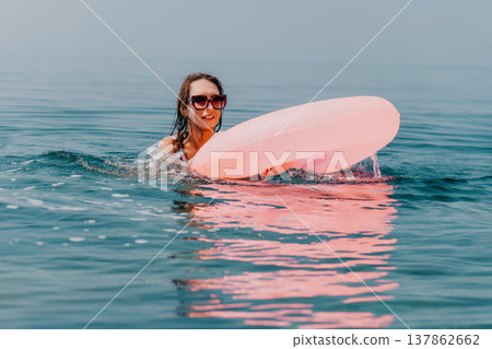 Woman swimming float, joyful summer vacation holiday at the misty sea with pink inflatable tube 137862662
