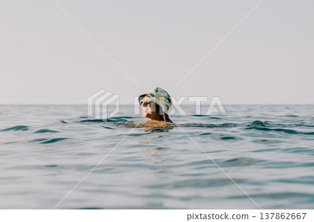 Woman Swimming Ocean Water - A woman wearing a swimming cap swims in the ocean. 137862667