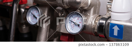 Complex residential heating manifold system with valves, gauges, and piping network. banner Complex residential heating manifold system with valves, gauges, and piping network. banner 137863109