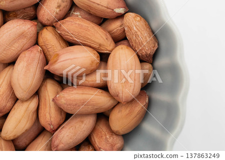 Raw peanuts with their thin skins still on, in a bowl. Raw peanuts with their thin skins still on, in a bowl. 137863249