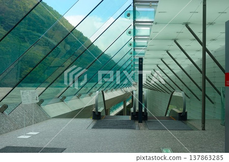 A glass-enclosed escalator at the Hakone Pola Museum of Art, offering views of the surrounding green mountains. A glass-enclosed escalator at the Hakone Pola Museum of Art, offering views of the surrounding green mountains. 137863285